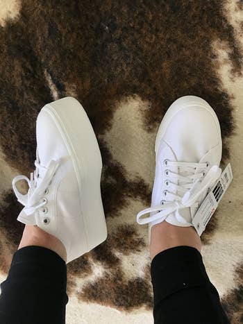 A reviewer posing in the white platform sneakers