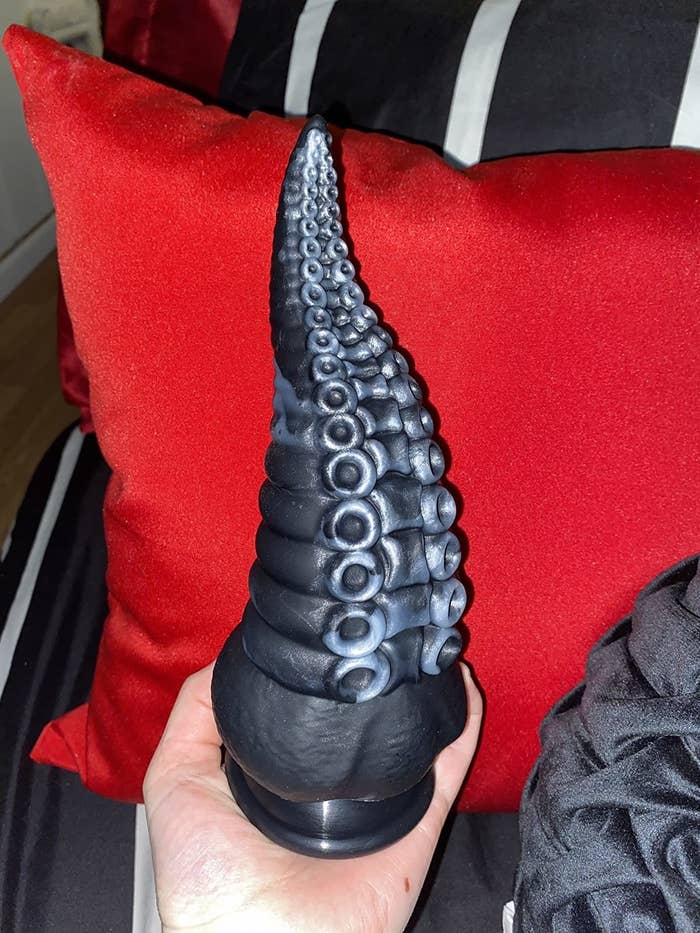 Reviewer holding black and silver tentacle dildo