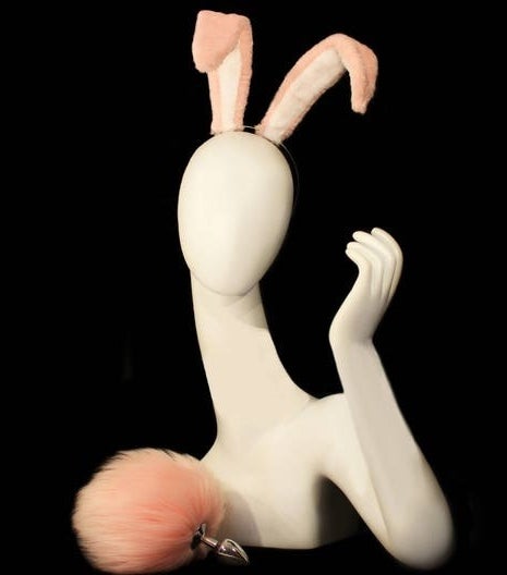 Mannequin wearing pink bunny ears next to pink faux bunny tail butt plug