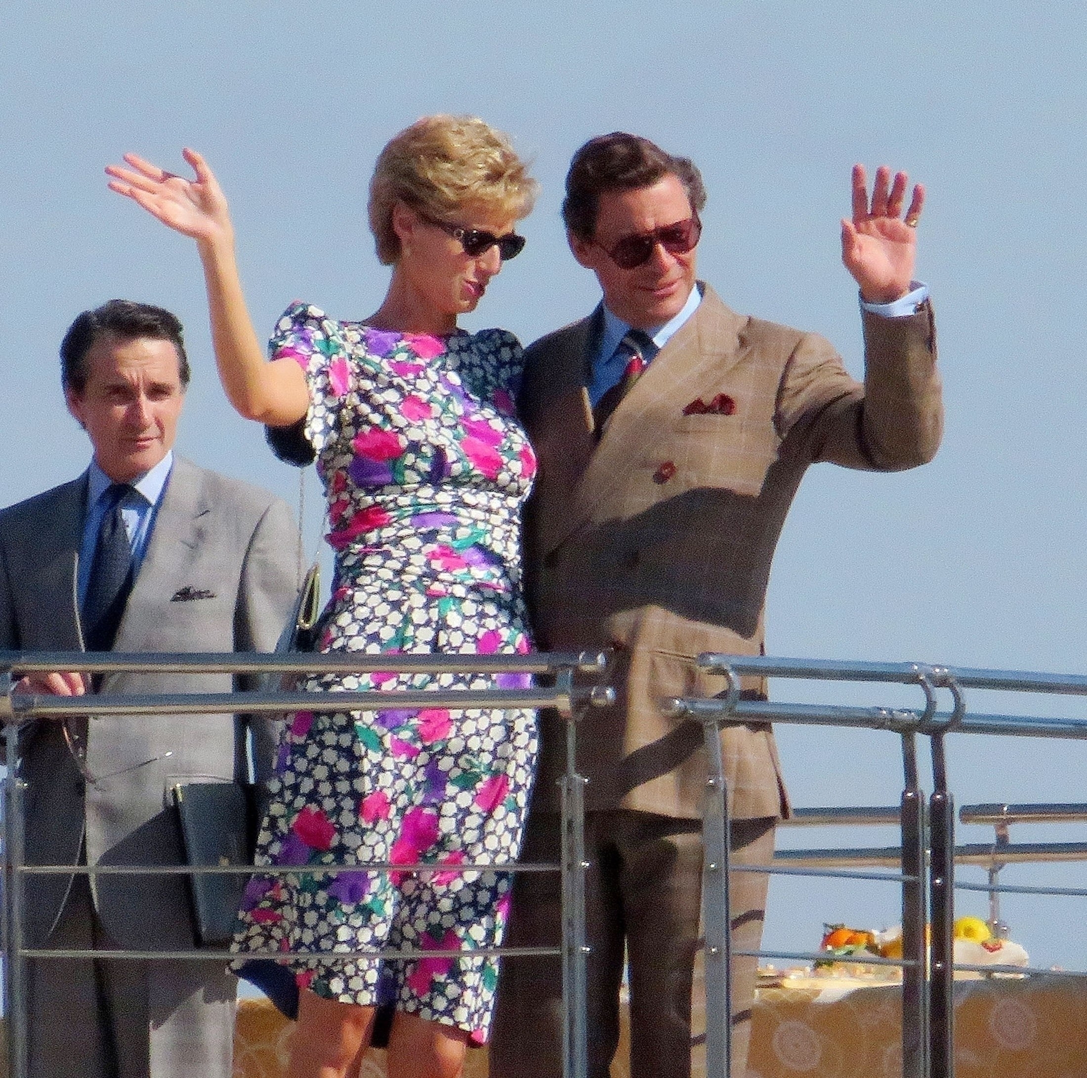 Elizabeth and Dominic waving as they film a scene aboard the yacht