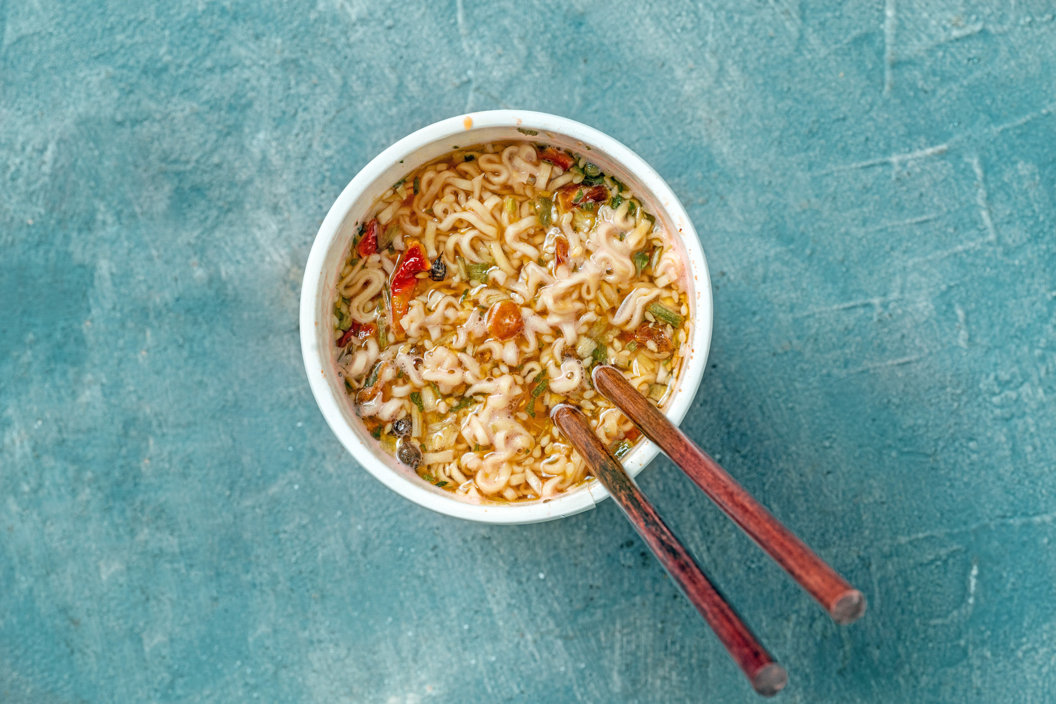 Chopsticks resting on the side of a bowl filled with noodles