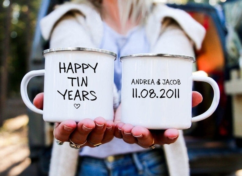 Model holding two white mugs with the left saying "Happy tin years" and the right saying "Andrea & Jacob, 11.08.2011"