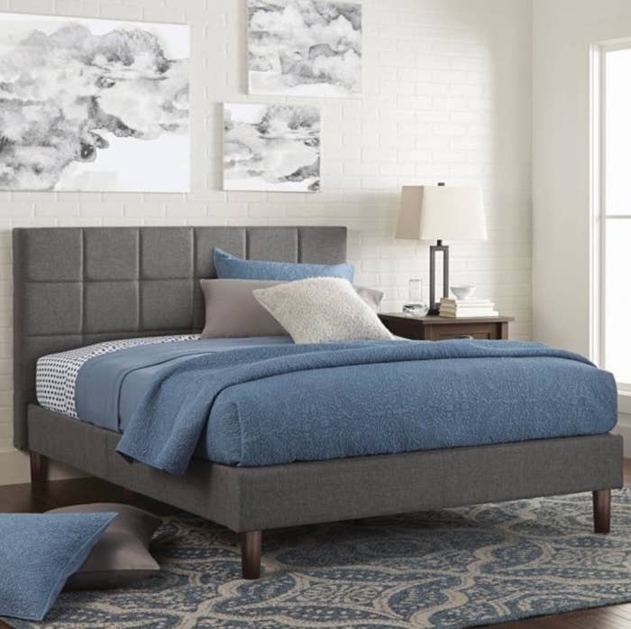 A grey, upholstered platform twin bed