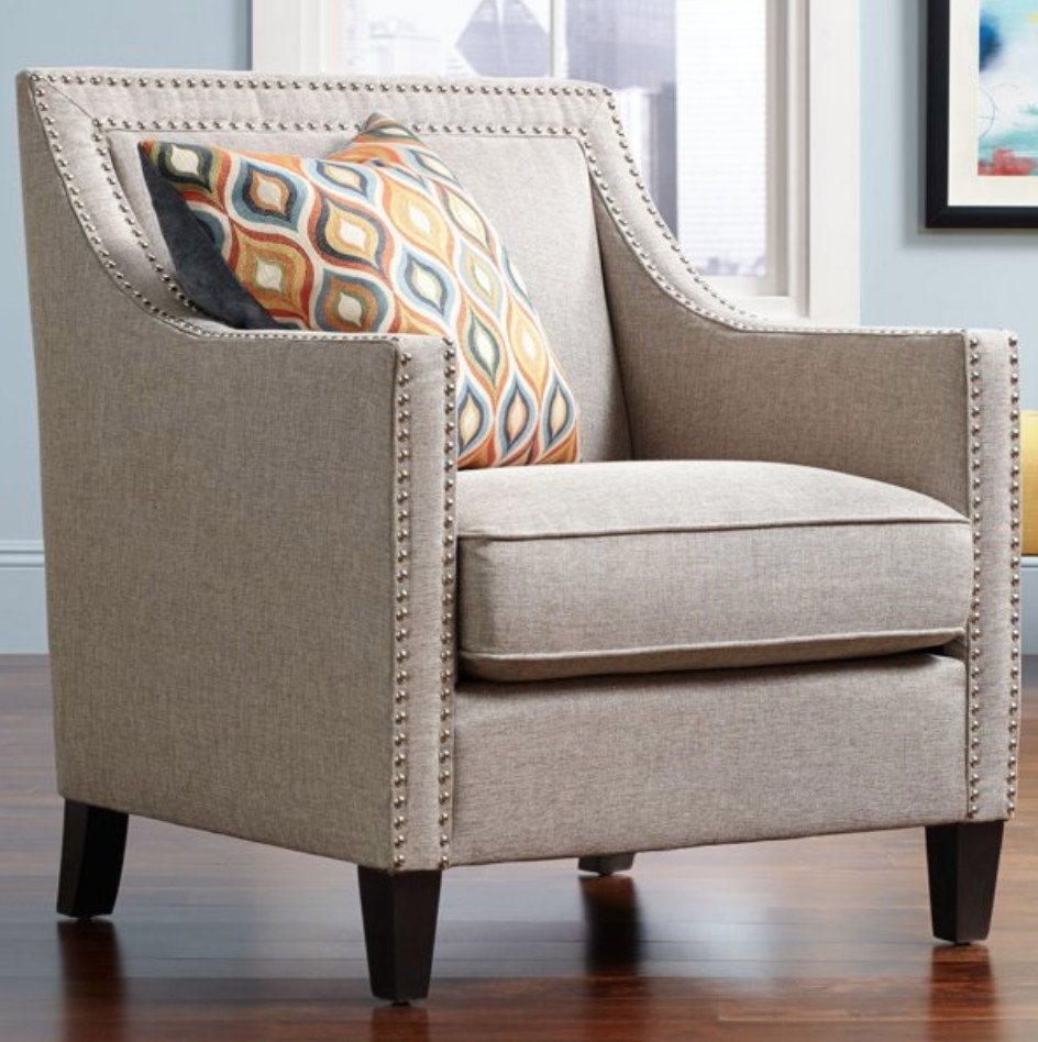A grey upholstered armchair with nailhead trim