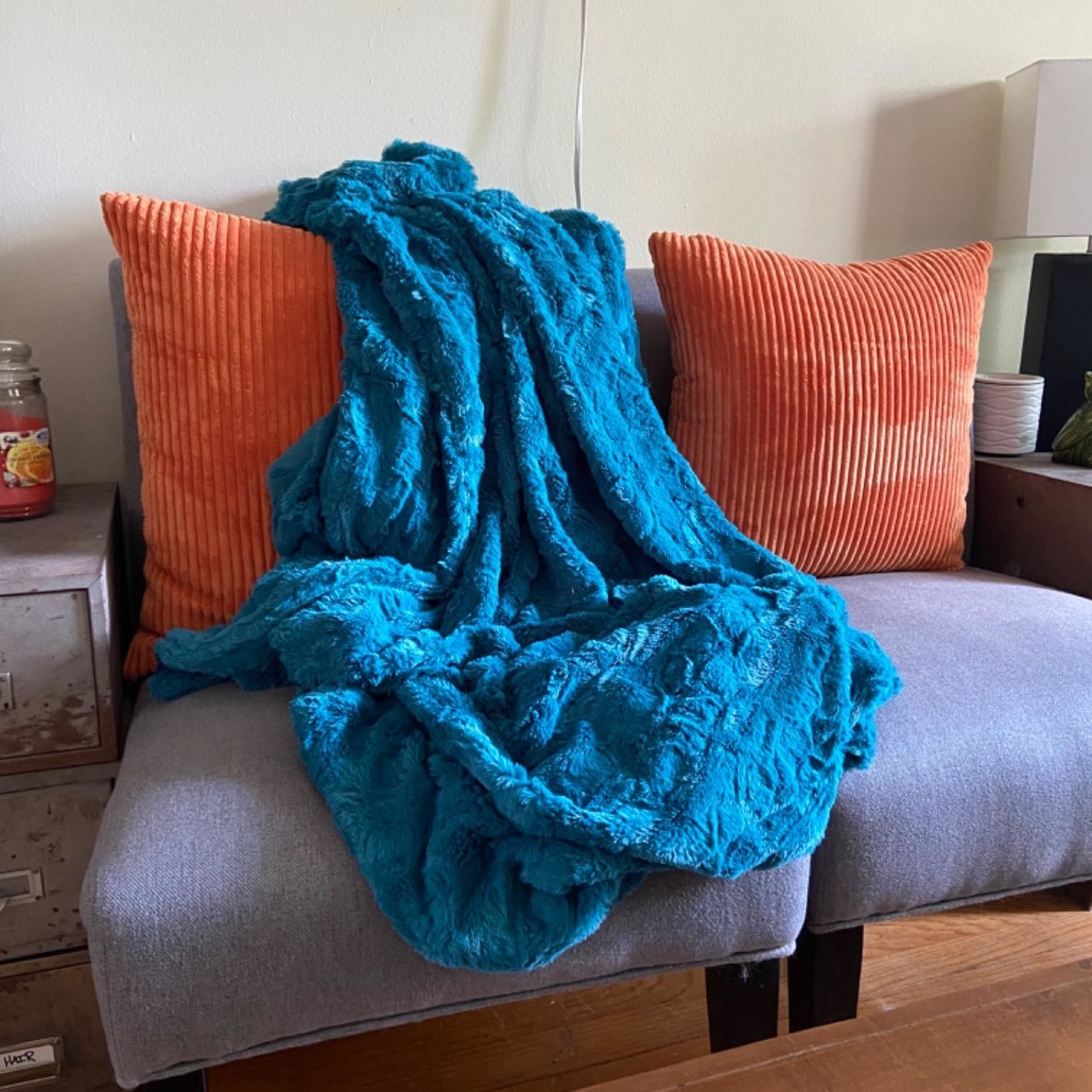 A reviewer photo with the faux fur throw blanket laying on their loveseat in blue