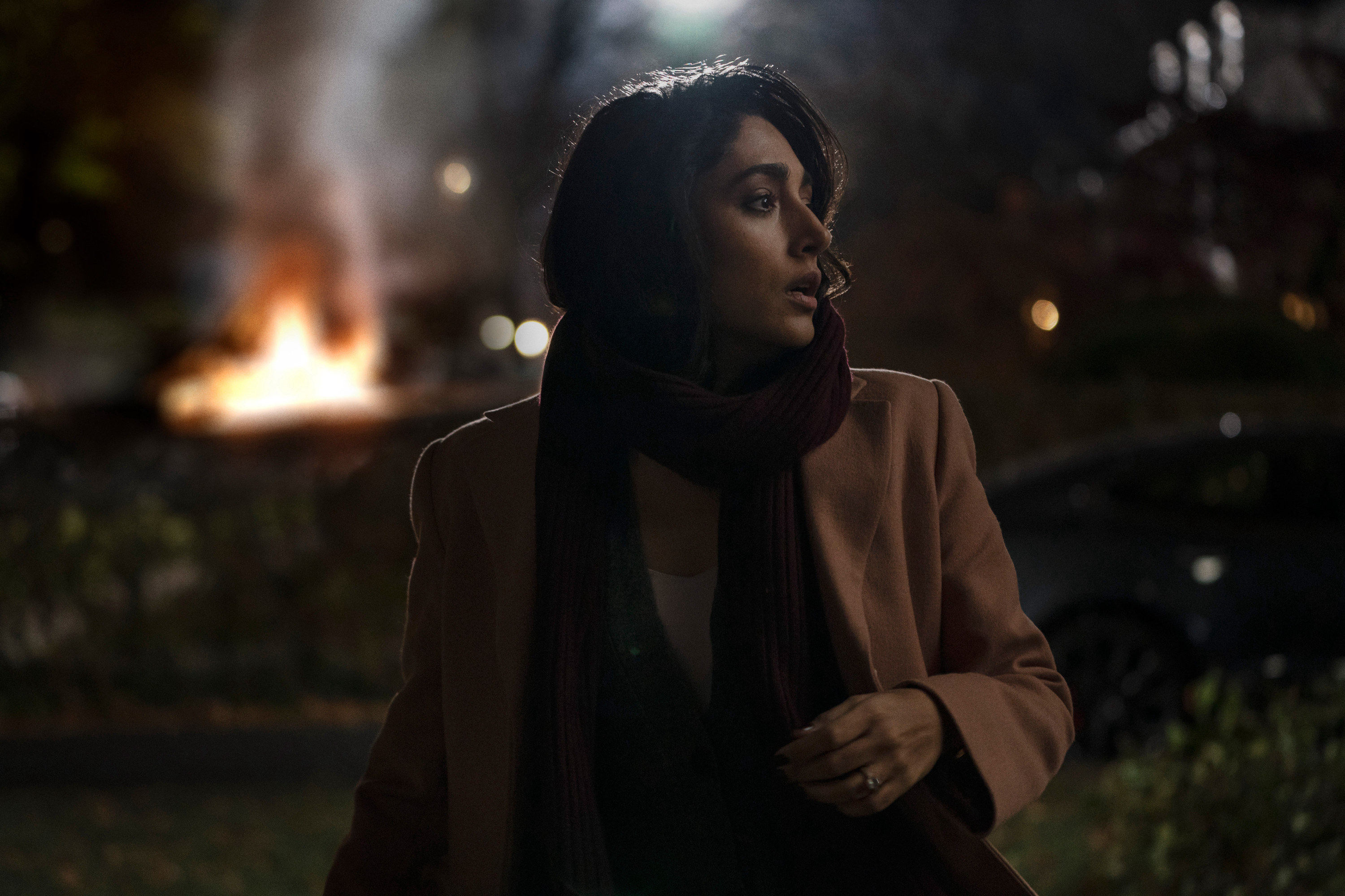 Golshiftah Farahani looks at something while a fire burns behind her