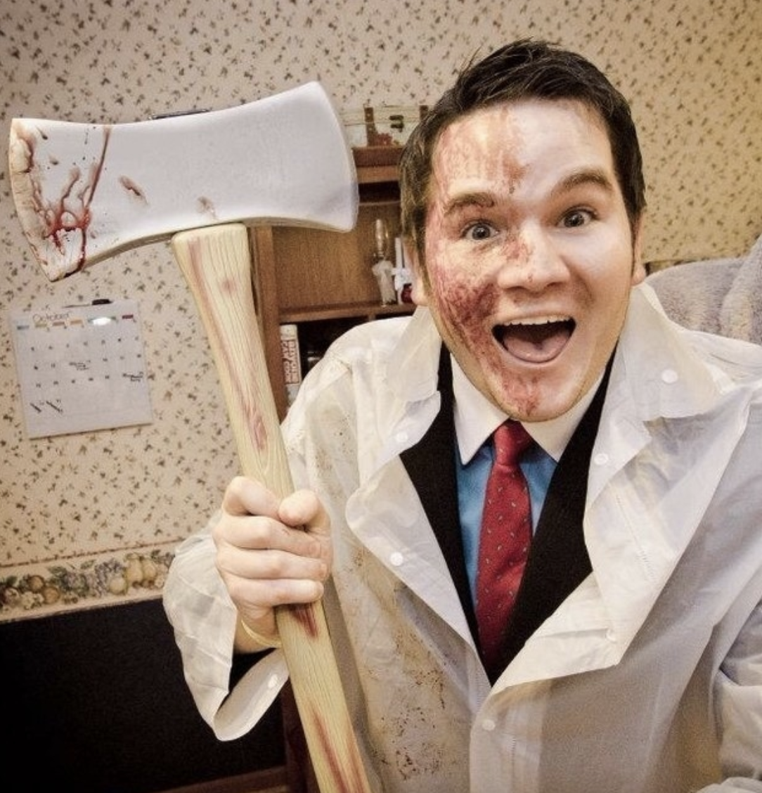 Someone wearing a plastic coat covered in blood while holding an axe