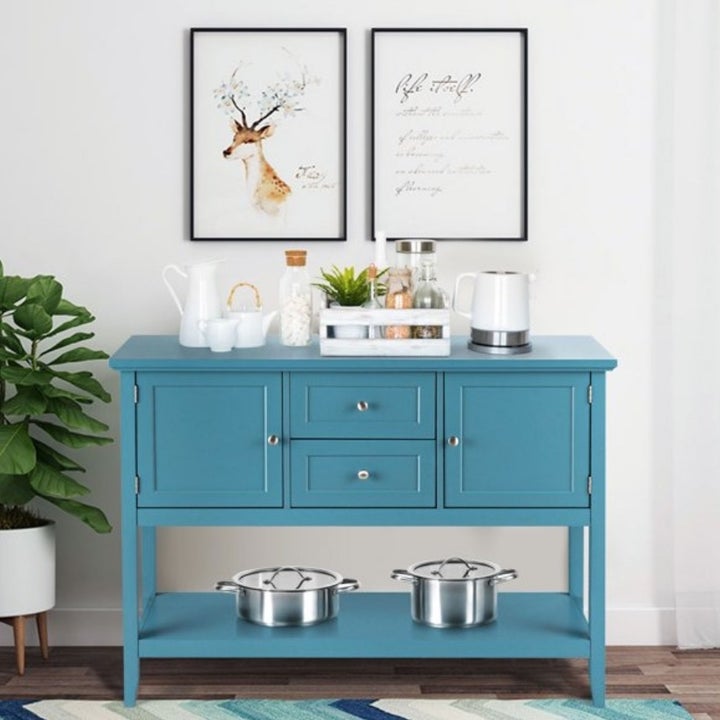 A blue console table with two cabinets, two drawers, and a bottom shelf