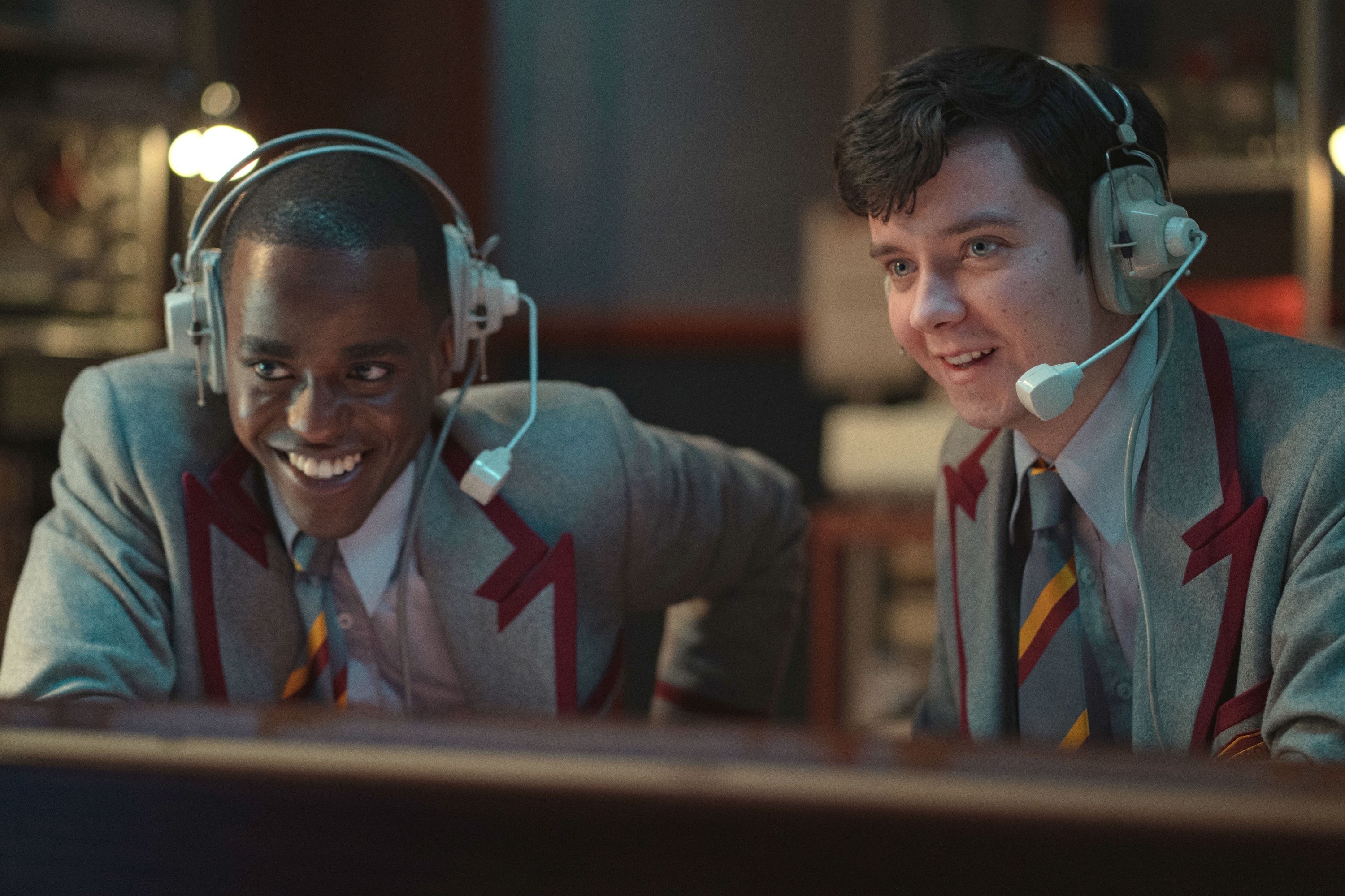 Ncuti Gatwa and Asa Butterfield commentate while wearing headsets