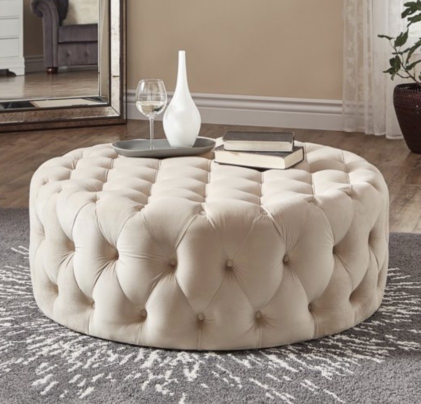 A beige velvet, tufted round cocktail ottoman
