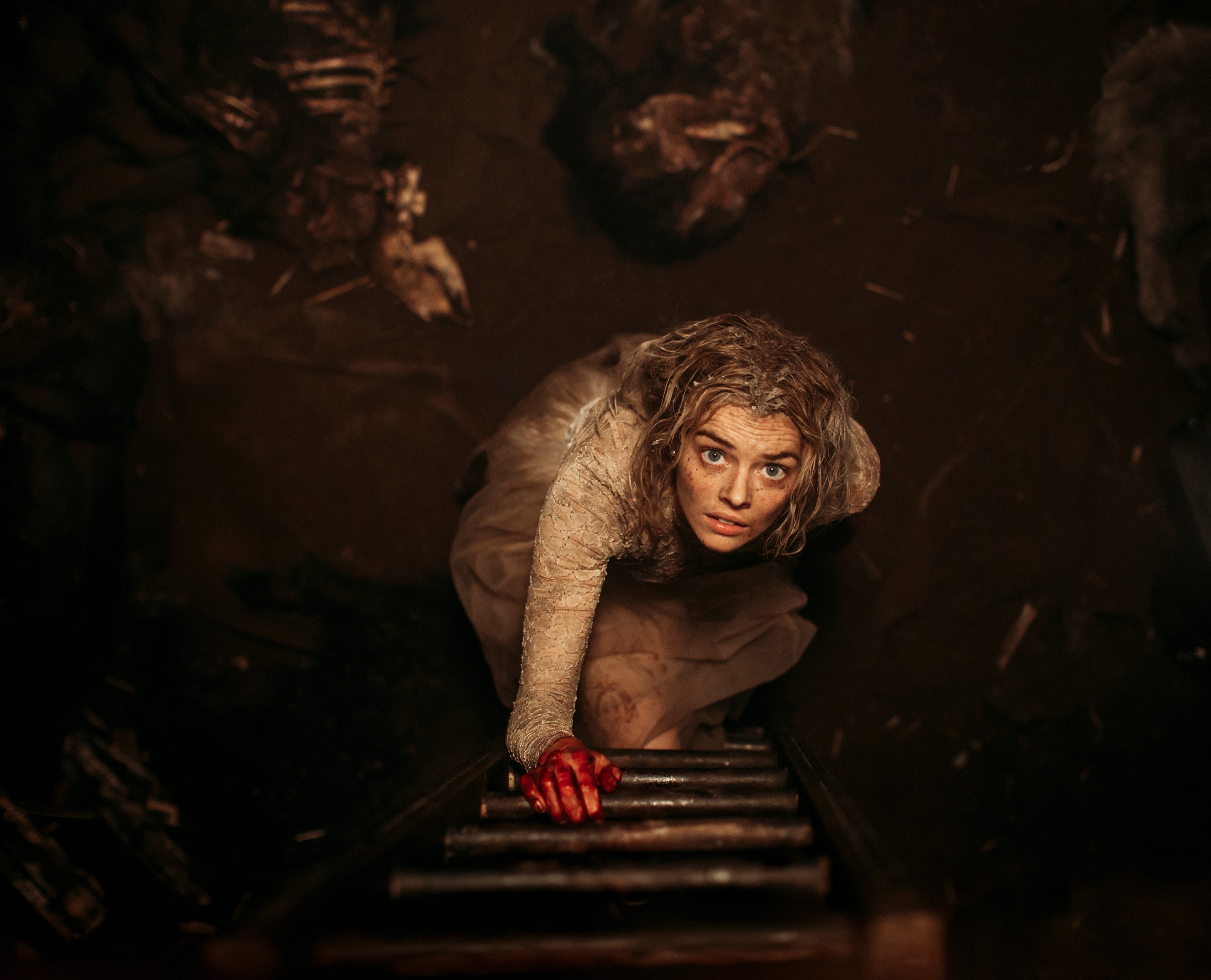 Samara Weaving crawling out of a pit with a bloody hand