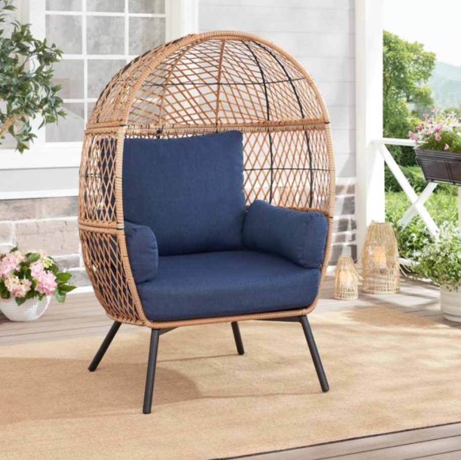A wicker egg chair with navy blue cushions