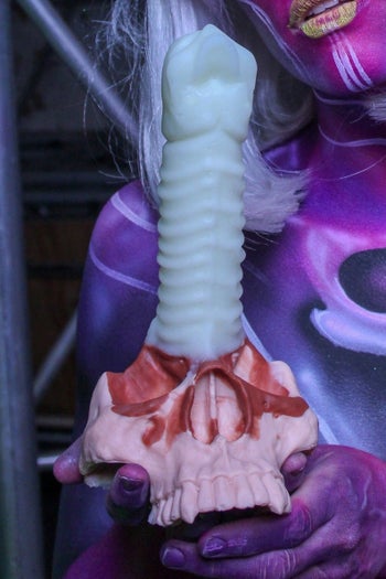 Model holding silicone dildo with skull for its base