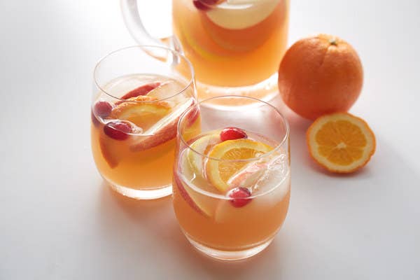 pitcher and glasses of rose sangria with fresh cranberries and orange slices