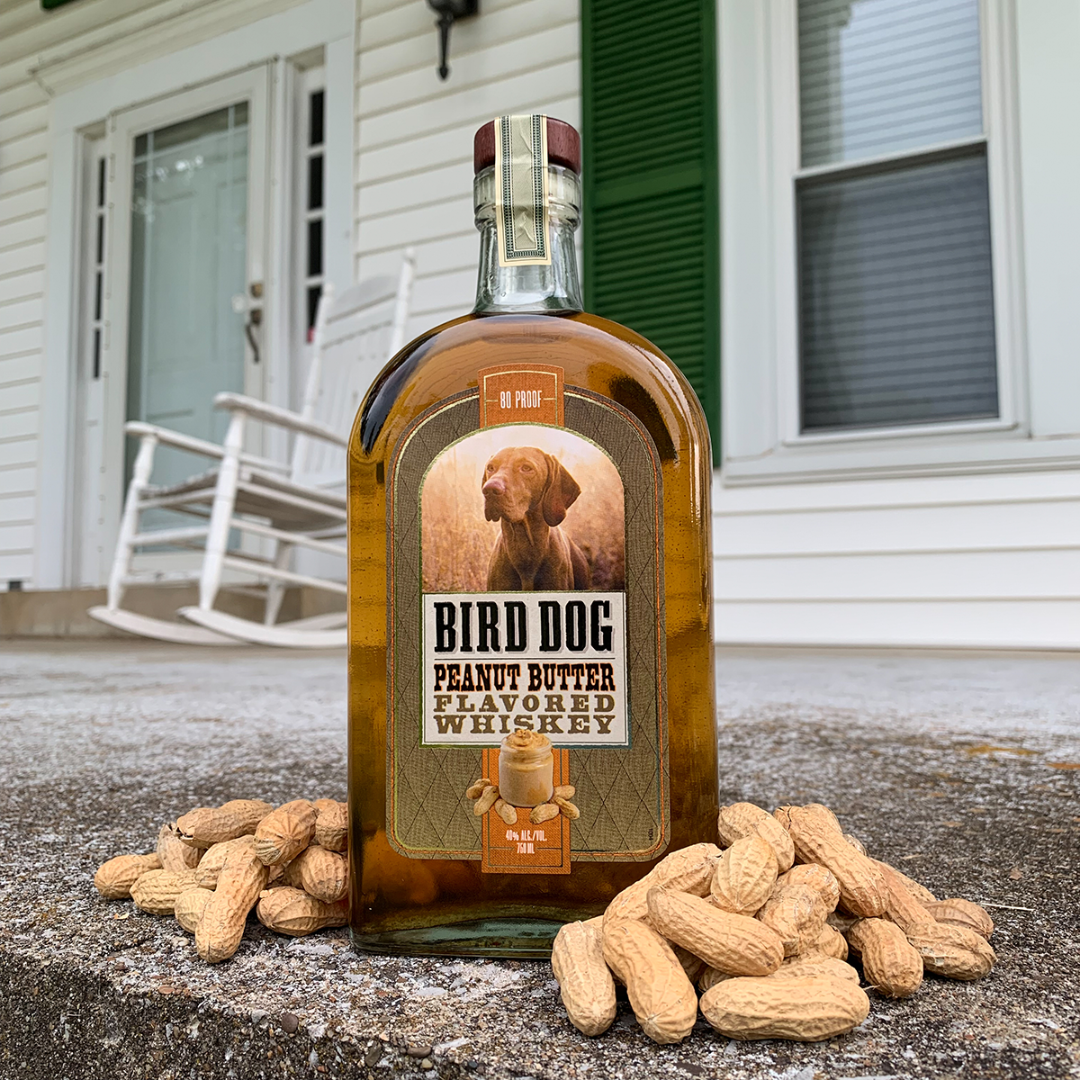 Bird Dog Peanut Butter Flavored Whiskey on a porch next to some peanuts