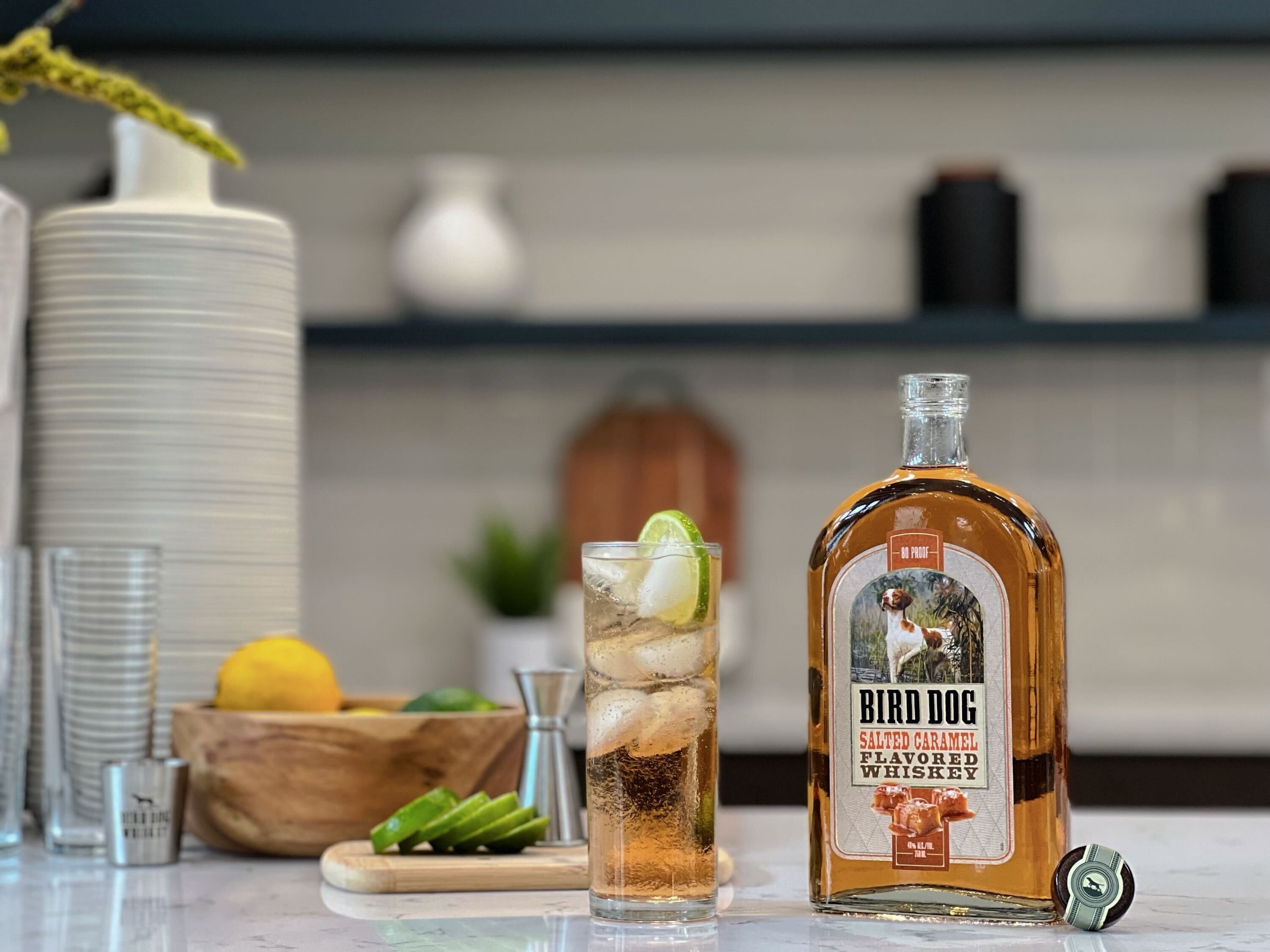 Bird Dog Salted Caramel Flavored Whiskey next to a cocktail in a glass on a kitchen counter