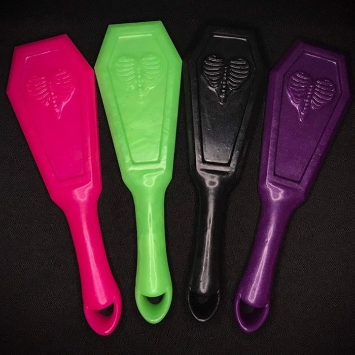 Coffin-shaped paddles in neon pink, neon green, black and purple