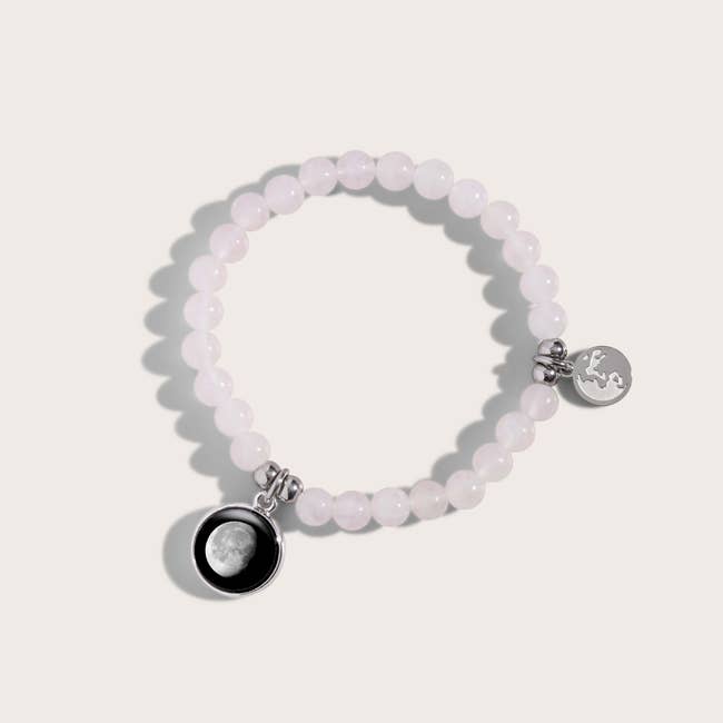 a light pink beaded bracelet with a charm of a moon