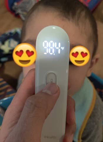 Reviewer taking temperature of their child, with the thermometer reading 98.4 degrees