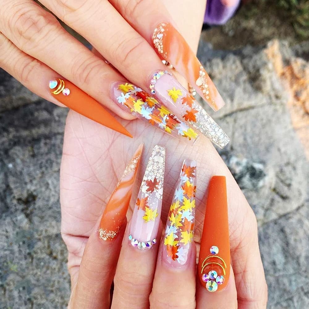 Model with holographic orange, yellow, and silver leaves on their nails