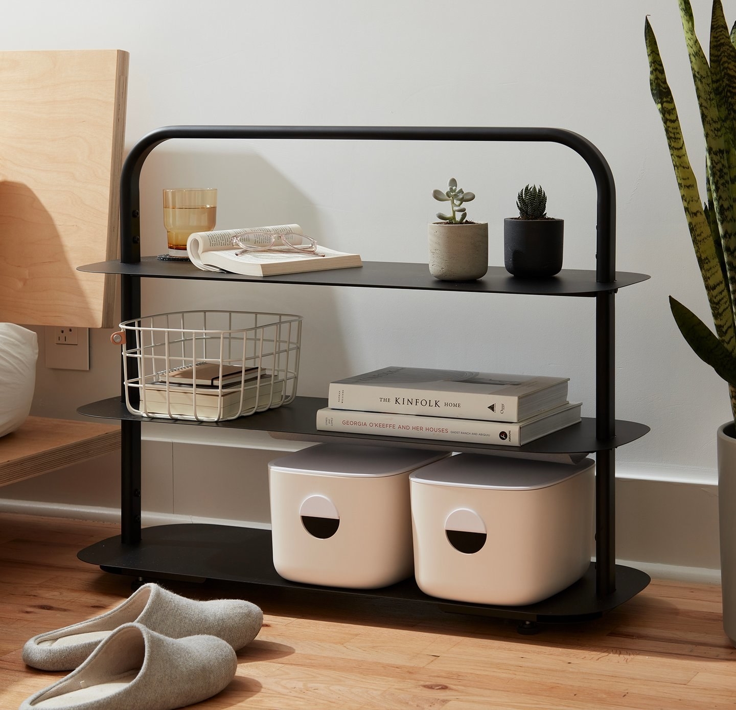 the three-tier rack with assorted books and containers on it