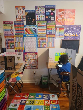 Reviewer's photo of their child homeschooling with the charts hanging on the wall