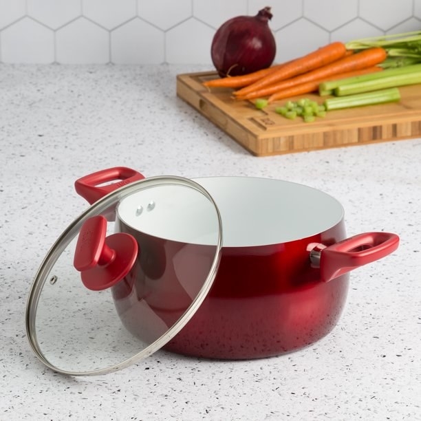 red dutch oven on a counter with its matching glass lid