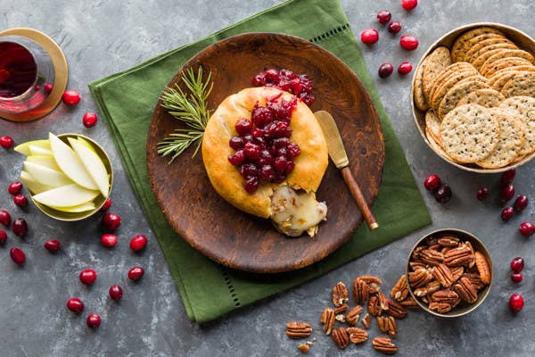 Baked brie on a serving platter with cranberries and crackers