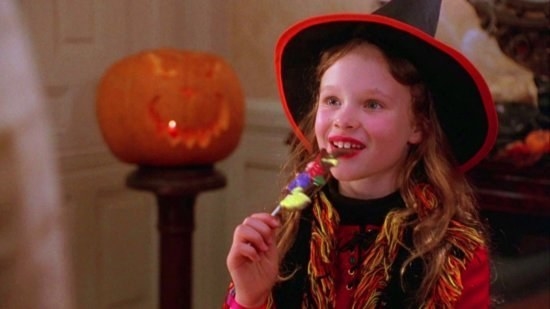 Dani, dressed as a witch, eating a Sanderson Sister lollipop