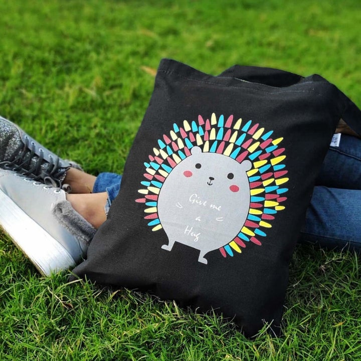 A person sitting down on grass with the porcupine bag by their legs