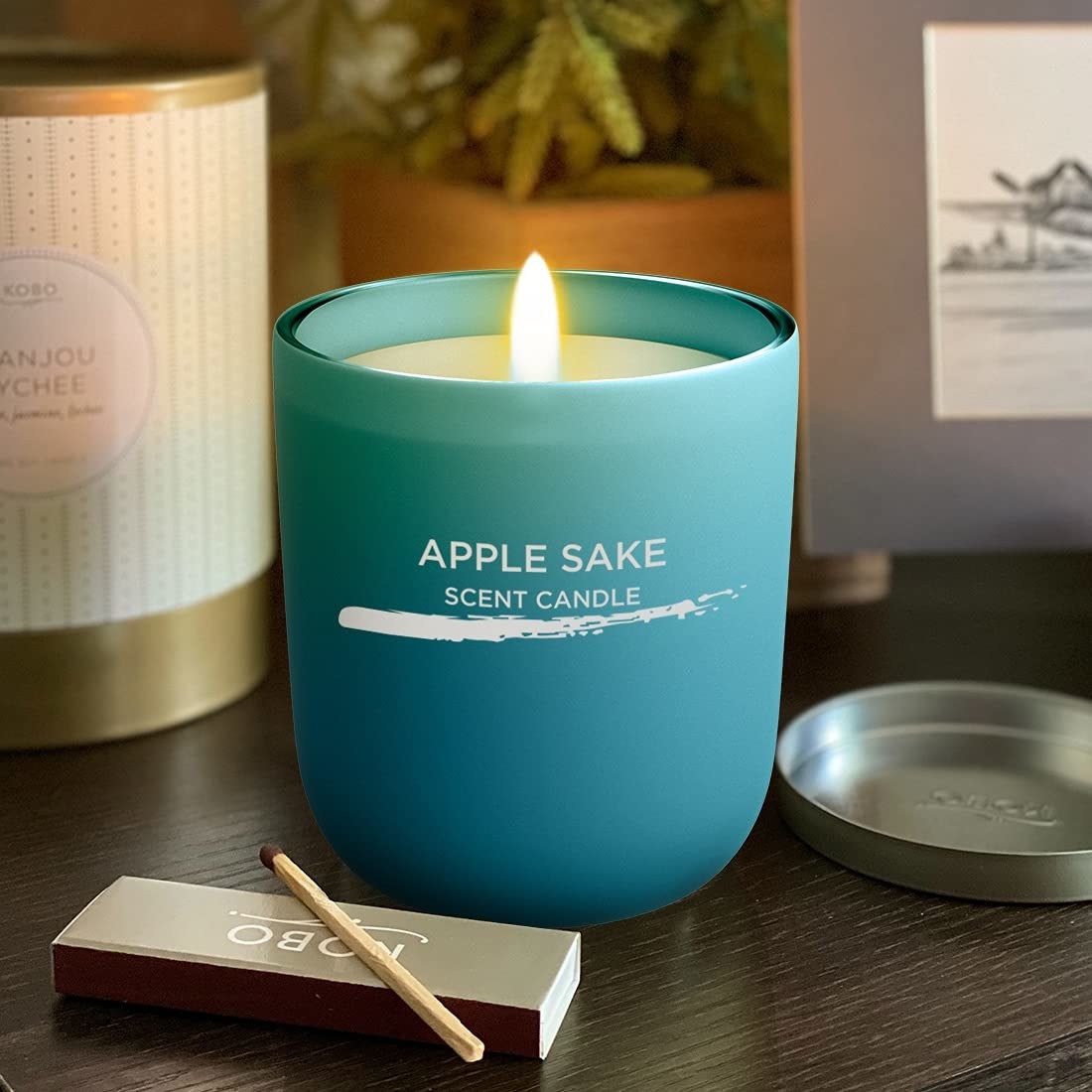 A blue scented candle on a table with a matchstick