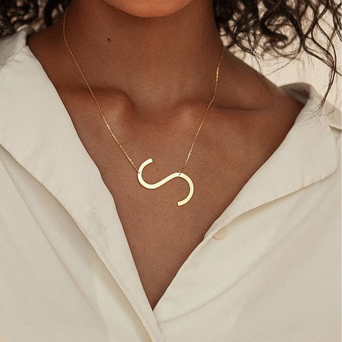 A person wearing a necklace with an "S" on it