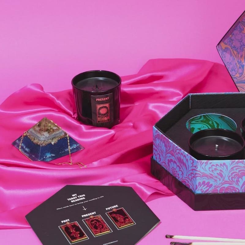 An image of The Tarot Trio candle set laid against a pink satin backdrop