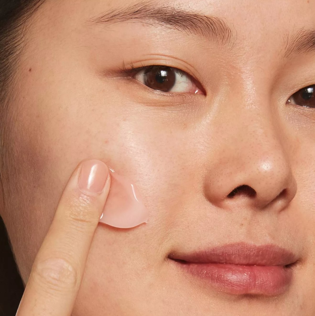 model using one finger to apply the moisturizer on their cheek
