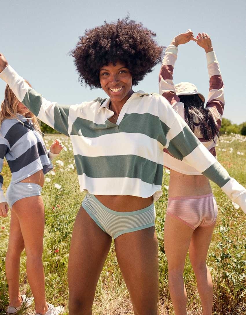 Three models dancing around in the striped cropped polos