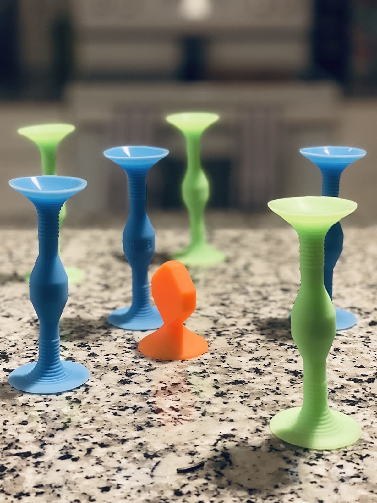 Reviewer&#x27;s image of green, blue, and orange Popdarts stuck to countertop