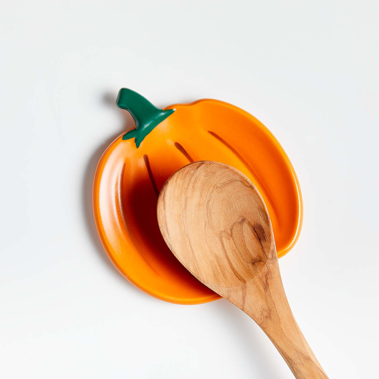 A spoon resting on an orange pumpkin spoon rest