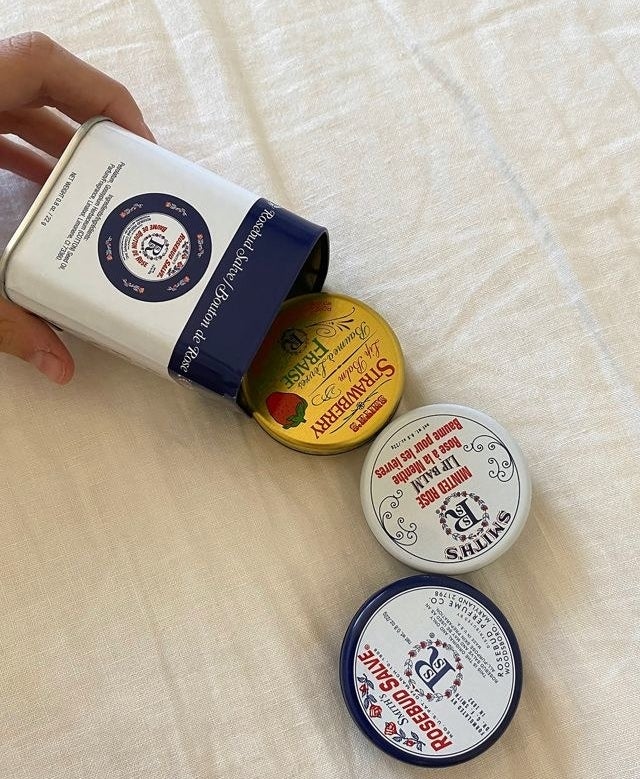 Model spilling three tins of lip balm onto a bed