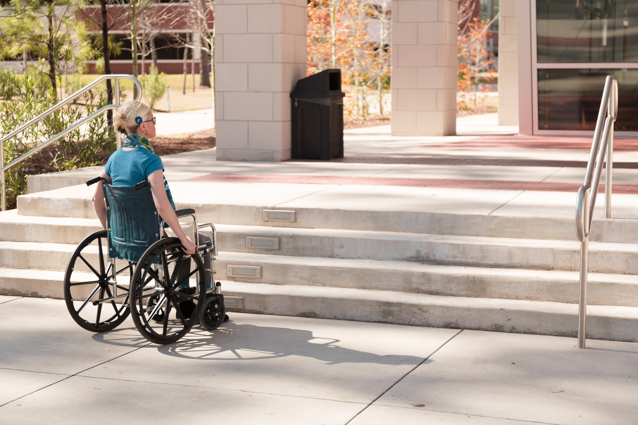 Person in wheelchair faced with inaccessible stairs to office or college building