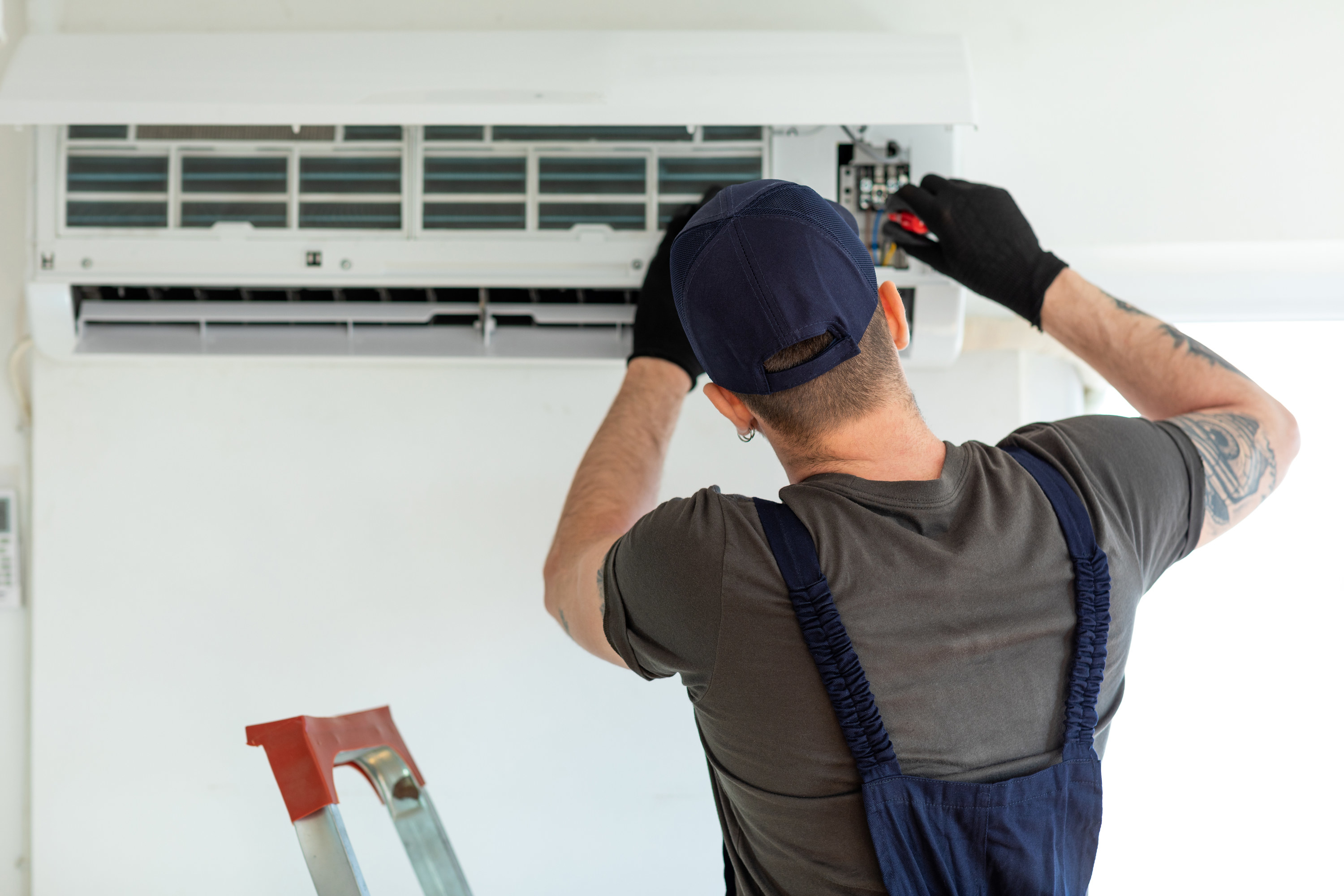 A maintenance worker fixing an air conditioning unit