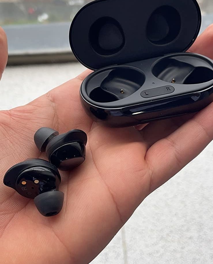 Reviewer holding black wireless earbuds and black case