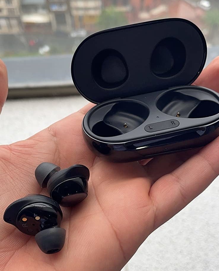 Reviewer holding black wireless earbuds and black case
