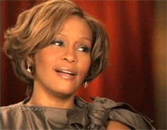 Whitney Houston laughing and smiling while pointing, then breaking smile to an annoyed face