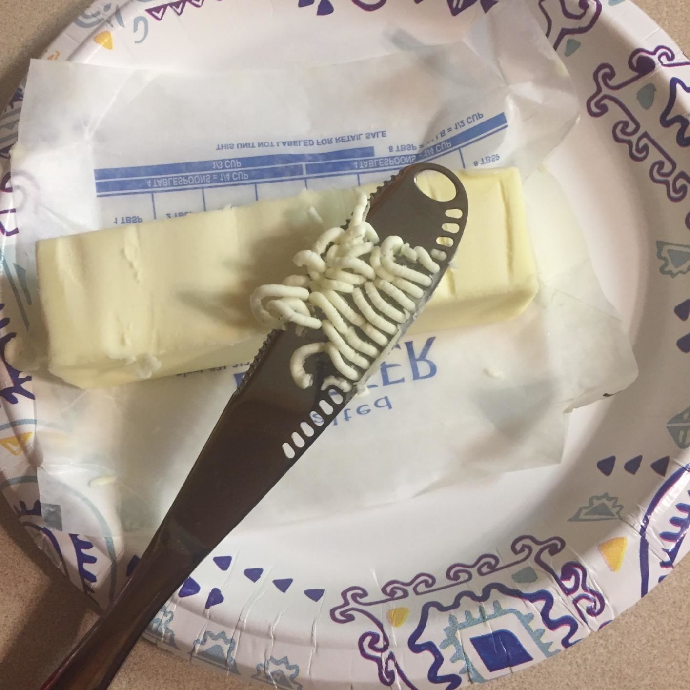 Reviewer&#x27;s knife with holes that pull up strips of butter from the stick