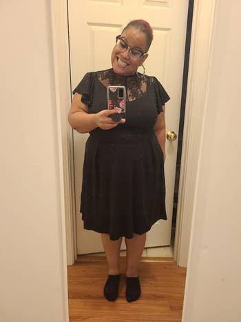 Reviewer wearing black cocktail dress with lace neckline