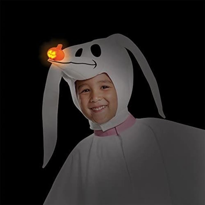 the same toddler showing the glowing pumpkin nose on the costume