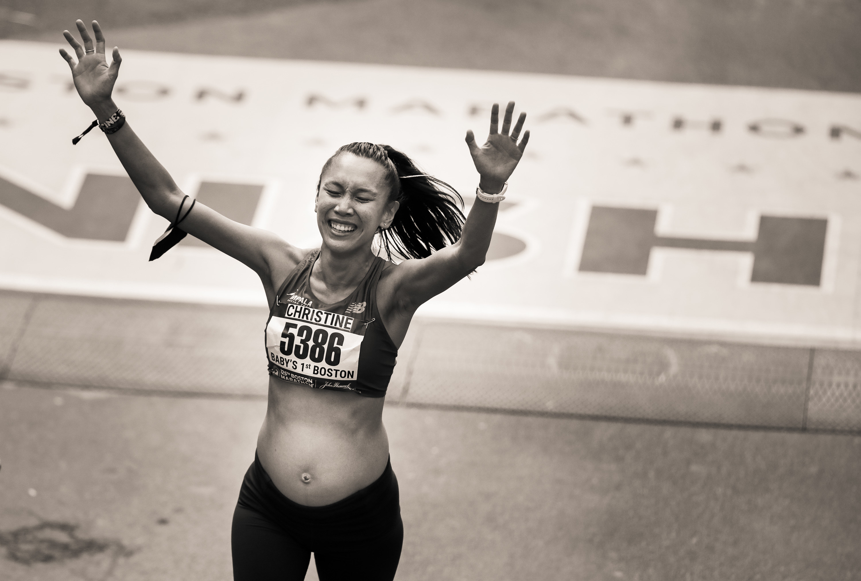 A pregnant runner with a Boston marathon bib that reads &quot;Baby&#x27;s 1st Boston&quot; crosses the finish line 