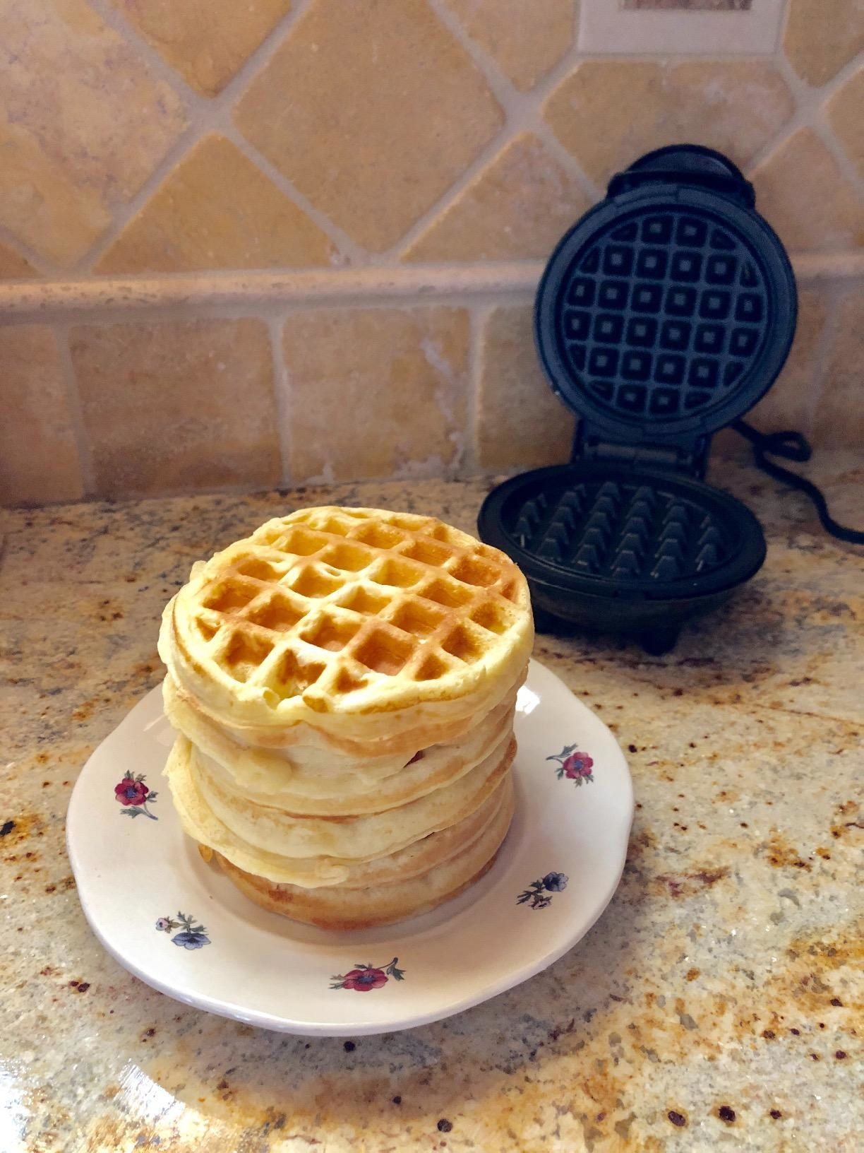 reviewer photo of a stack of mini waffles on a plate in front of the mini waffle maker