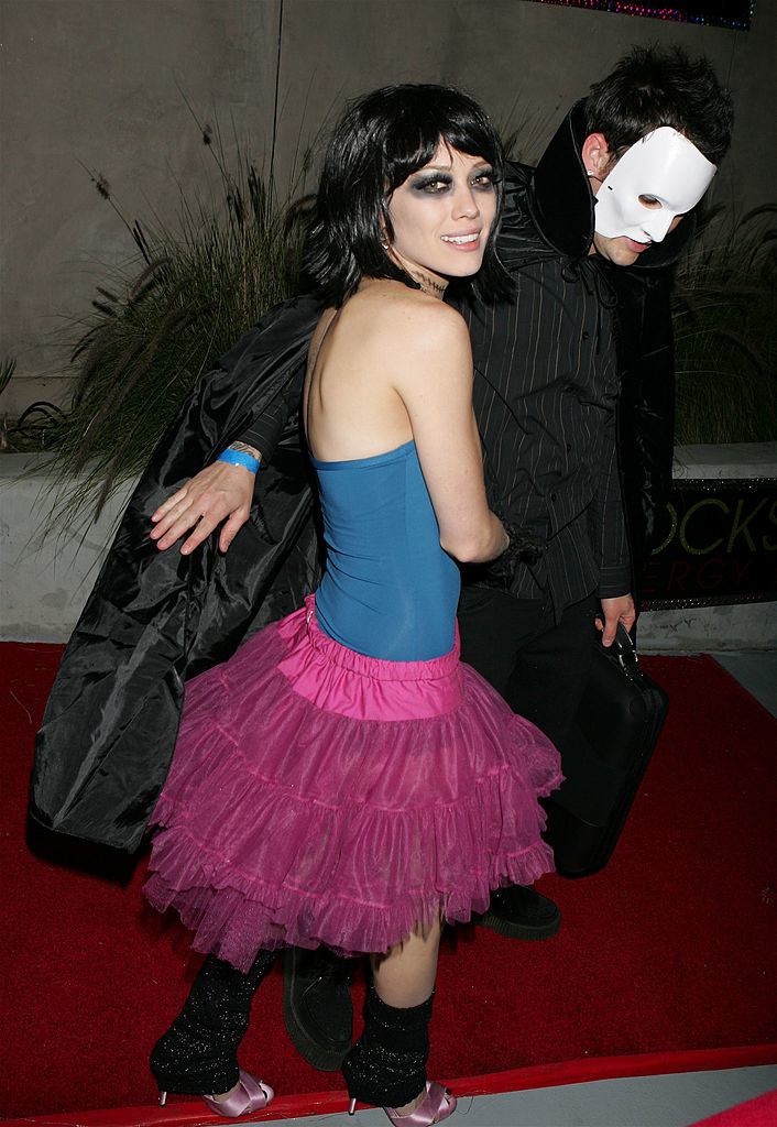 he has a white mask on and she has black eye makeup and a pink tutu