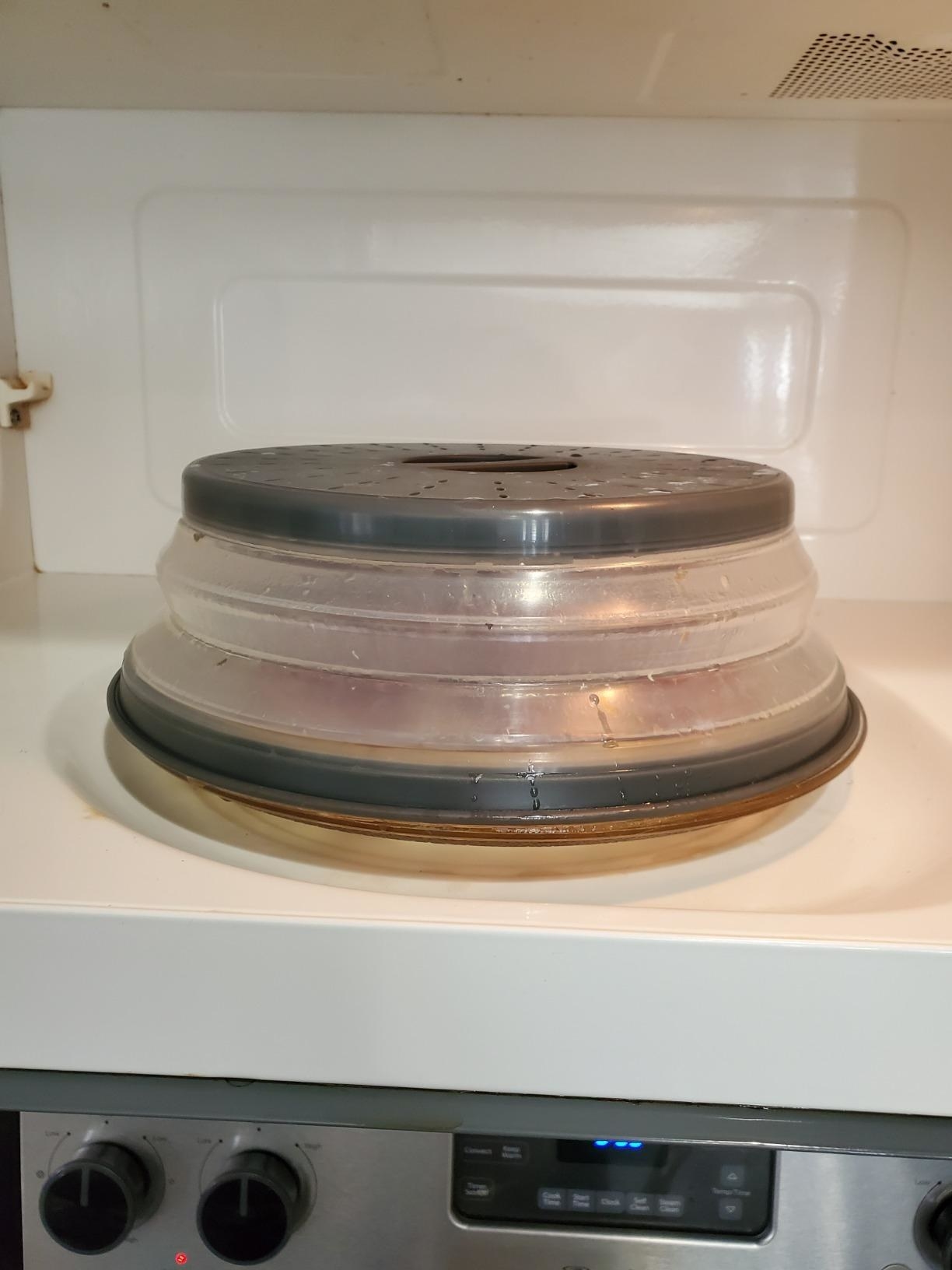 a plate of food with the lid on it in the microwave